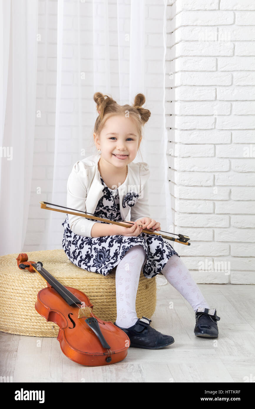 kleines Mädchen sitzt, hält einen Bogen und Zunge zeigen Stockfoto