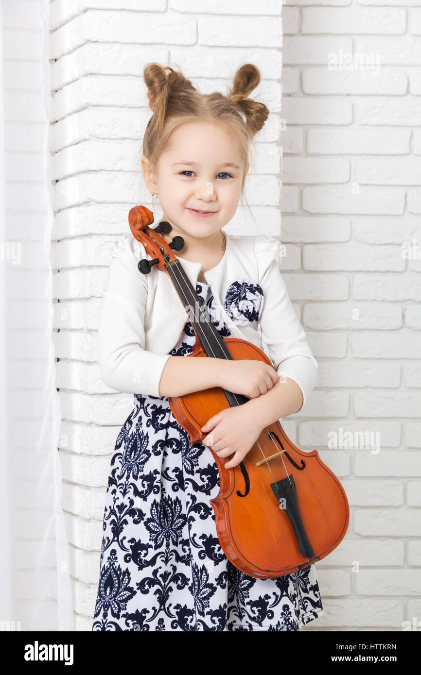 kleines Mädchen umarmt eine Geige Stockfoto