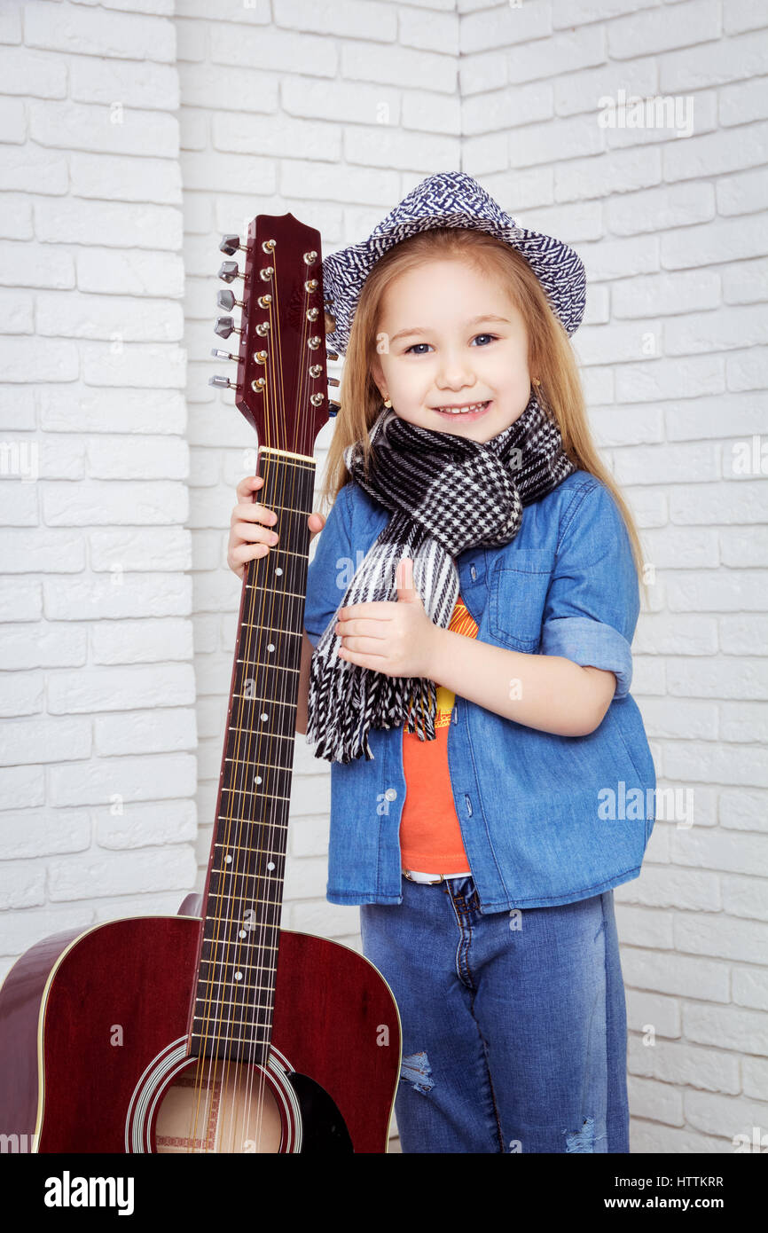 kleines Mädchen mit Hut halten Gitarre Stockfoto