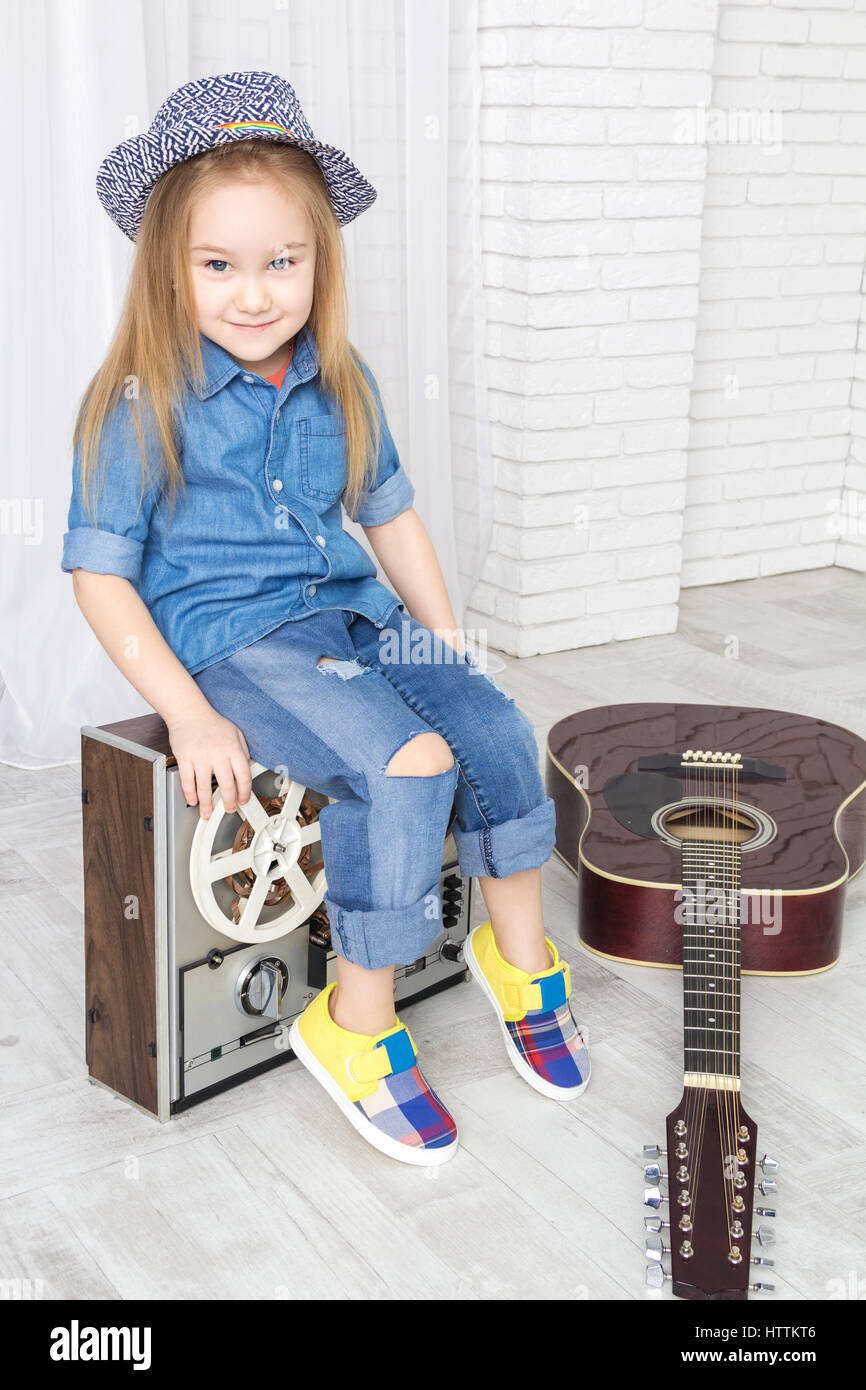 kleines Mädchen sitzt auf Retro-Tonbandgerät Stockfoto