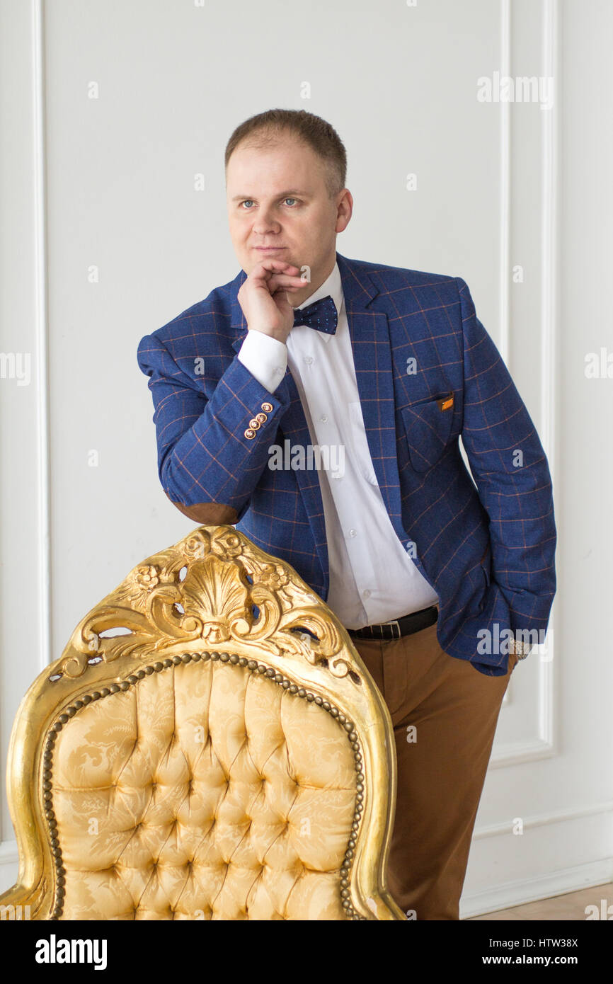 Männer mit Stuhl. Voller Länge überzeugt junge Unternehmer stehen in der Nähe von Vintage Sessel während auf grau isoliert. Stockfoto