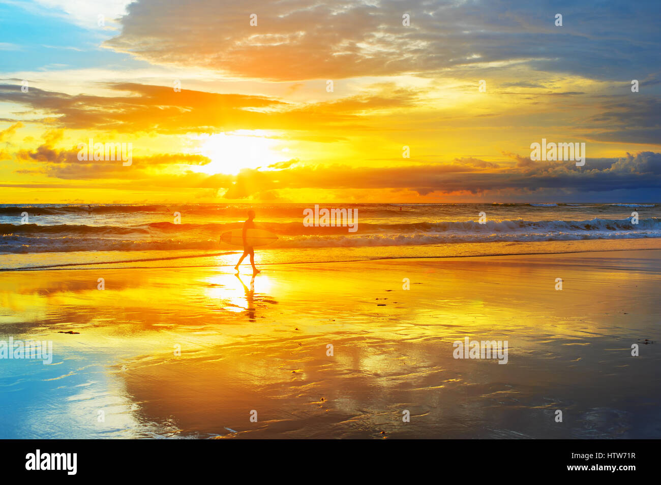 Surfer mit Surfbrett am Strand bei Sonnenuntergang zu Fuß. Insel Bali, Indonesien Stockfoto