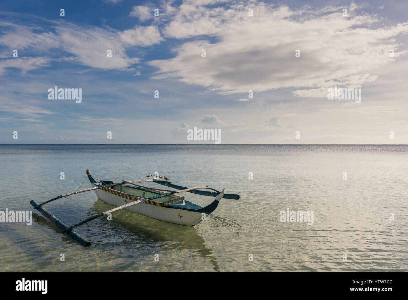 Traditionelle Filipino Fischerboot mit Möwen auf die Ausleger in einem ruhigen Meer schweben. Stockfoto