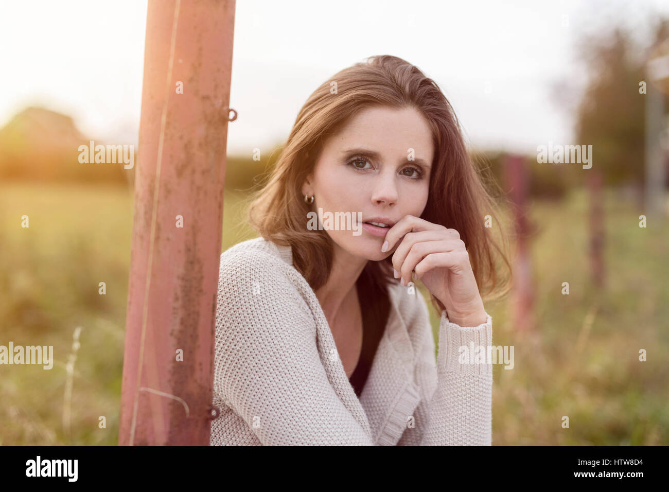 Junge Frau sitzt auf einer Weide Stockfoto