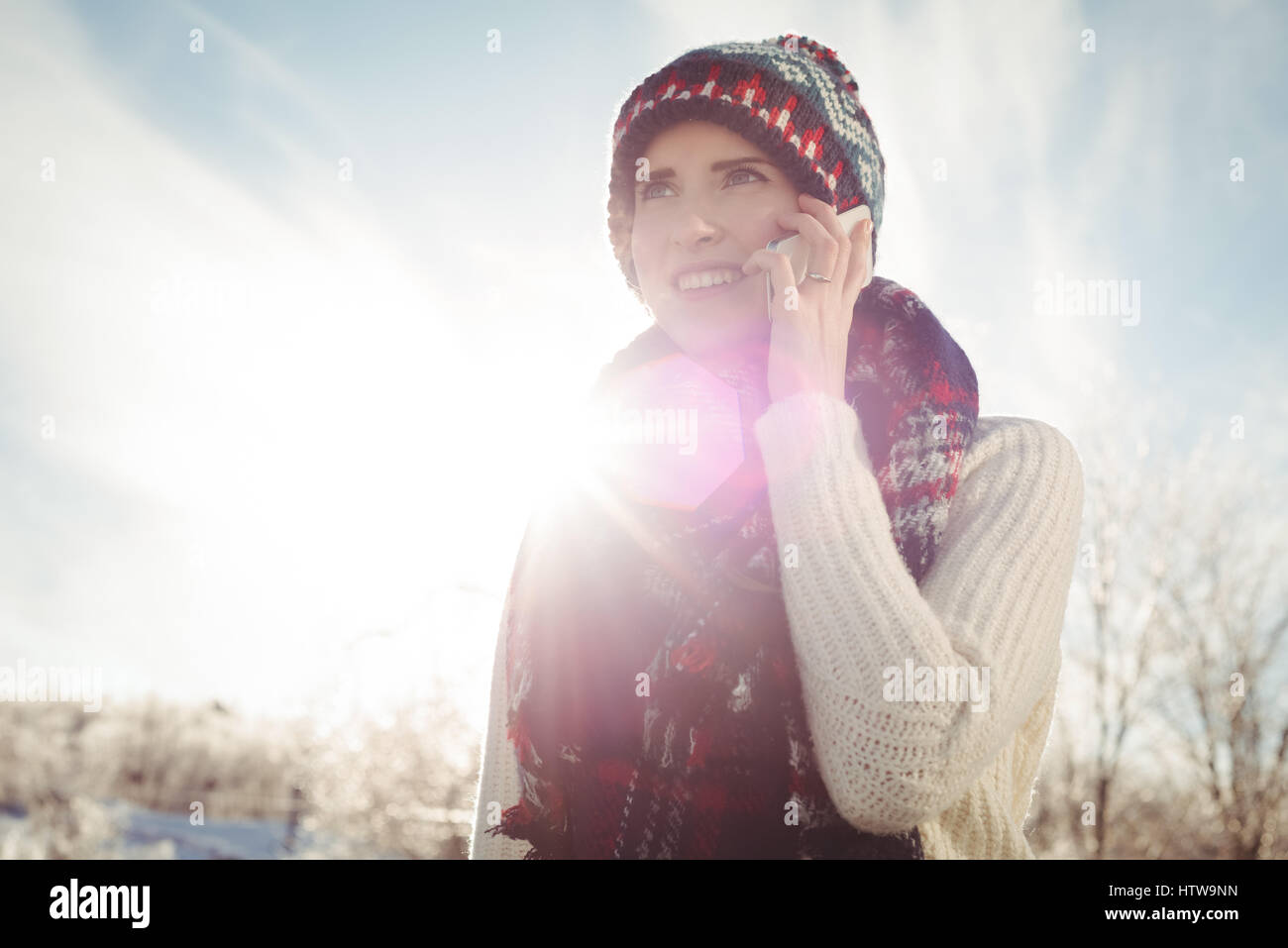 Lächelnde Frau in Winterkleidung am Telefon sprechen Stockfoto