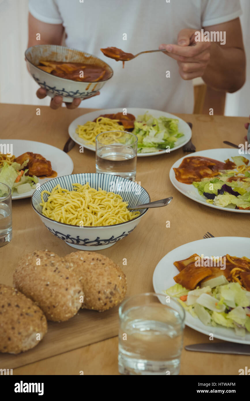 Mittleren Bereich des Menschen etwas zu Essen am Esstisch Stockfoto