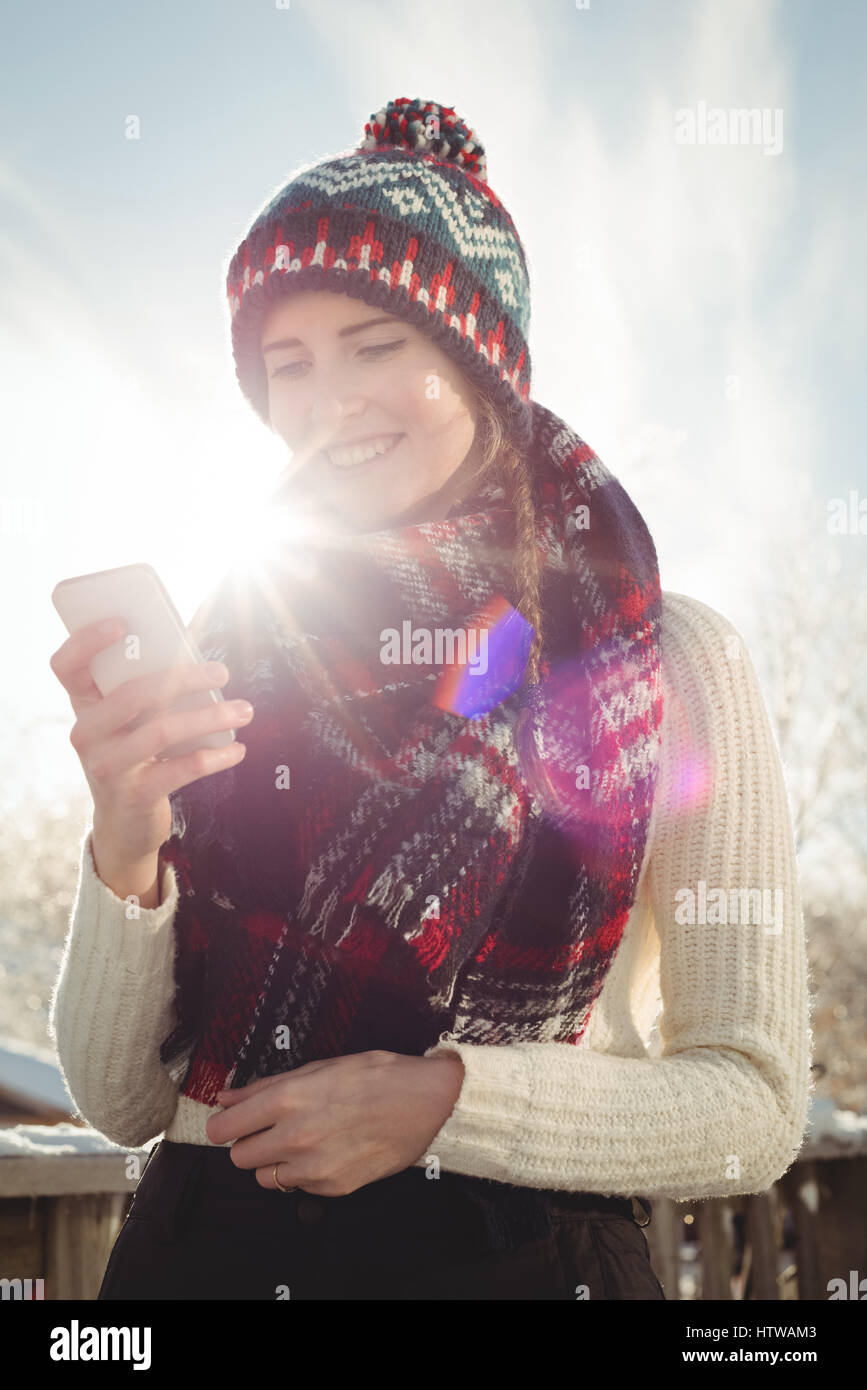 Lächelnde Frau in Winterkleidung eine Textmitteilung zu schreiben Stockfoto