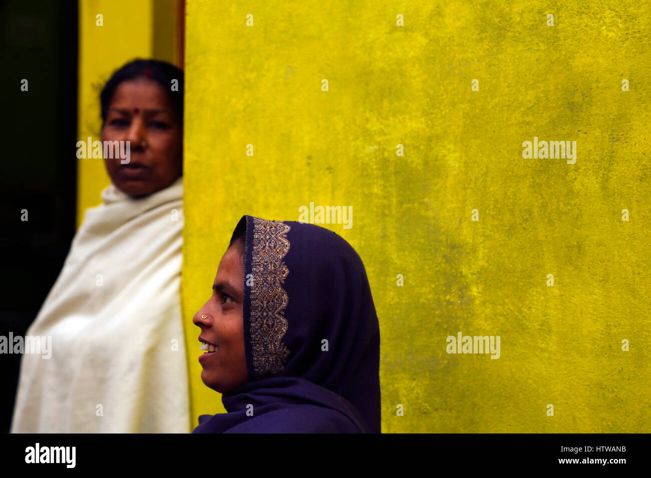 Eine indische Frau vor einem gelben Wand und anderen in den Hintergrund, Khajuraho, Indien Stockfoto