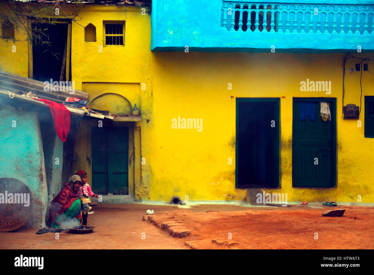 Eine indische Frau mit der Tochter in einem bunten Schal sitzt vor ihrem Haus, Khajuraho, Indien Stockfoto