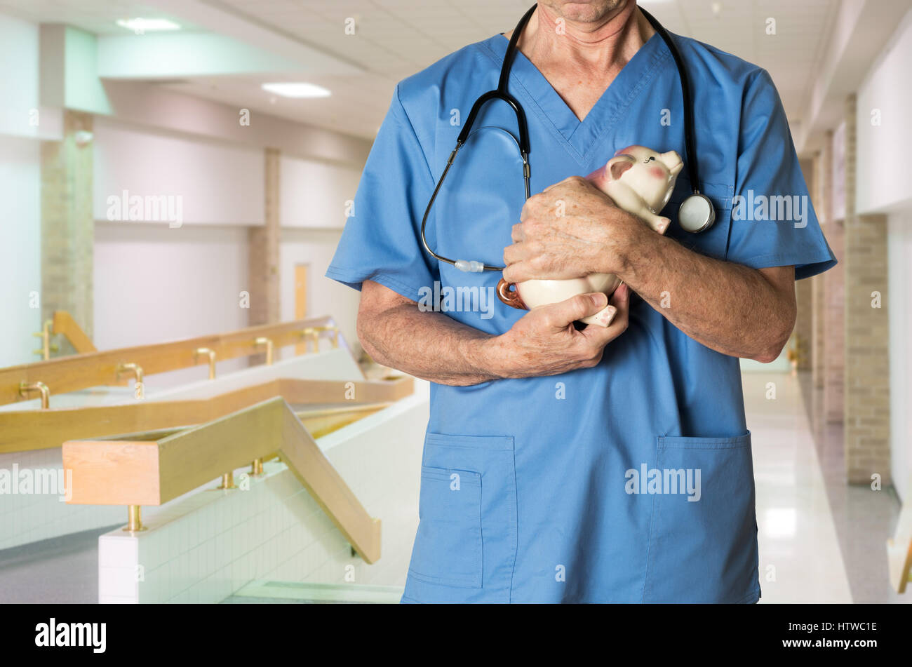 Leitender Arzt in Scrubs mit Sparschwein Stockfoto