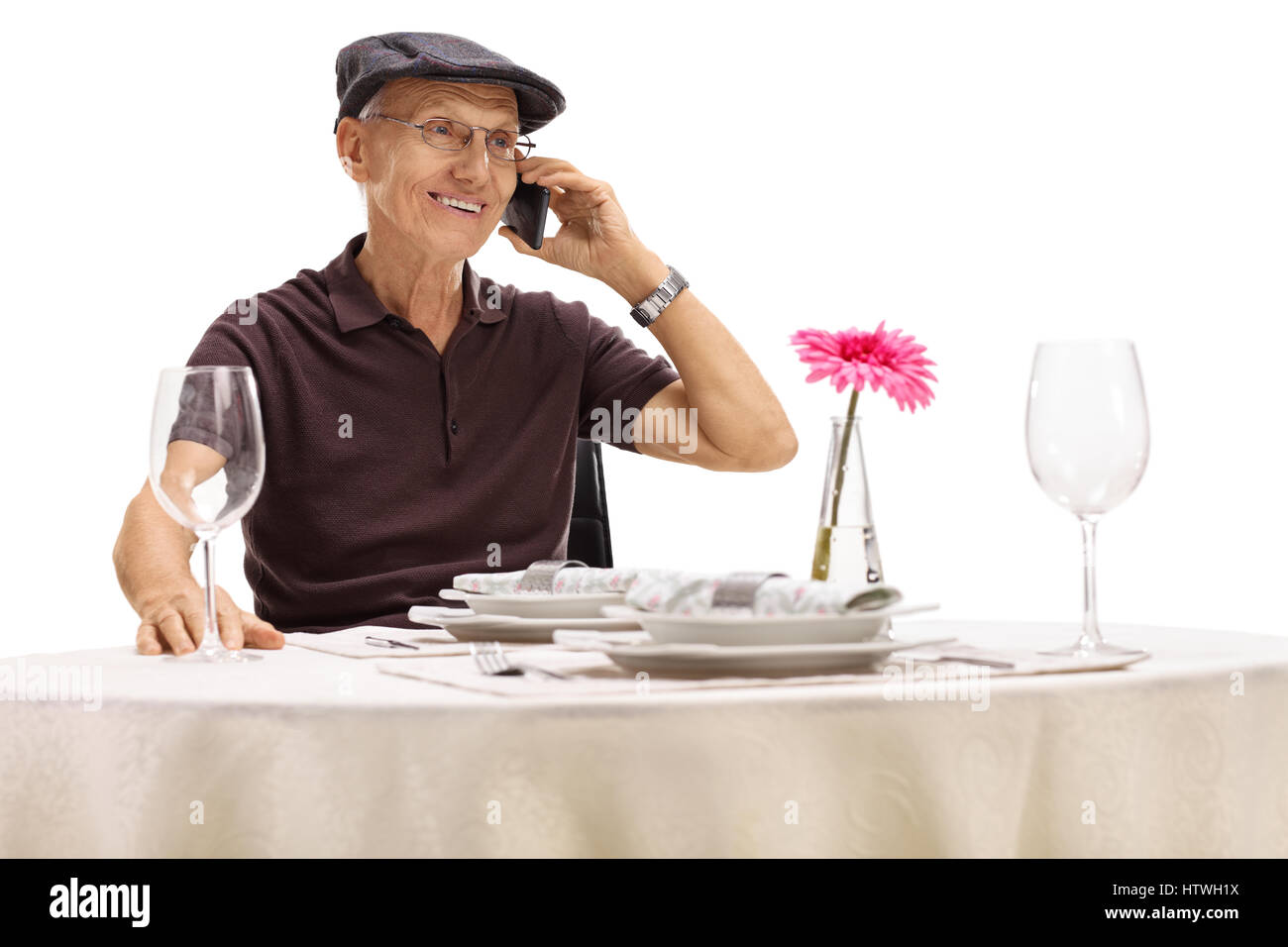 Senior an einen Tisch im Restaurant sitzen und telefonieren isoliert auf weißem Hintergrund Stockfoto