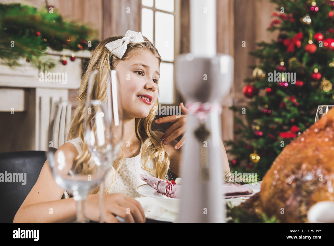 Niedliche lächelnde Mädchen sitzen am Tisch Urlaub zur Weihnachtszeit Stockfoto