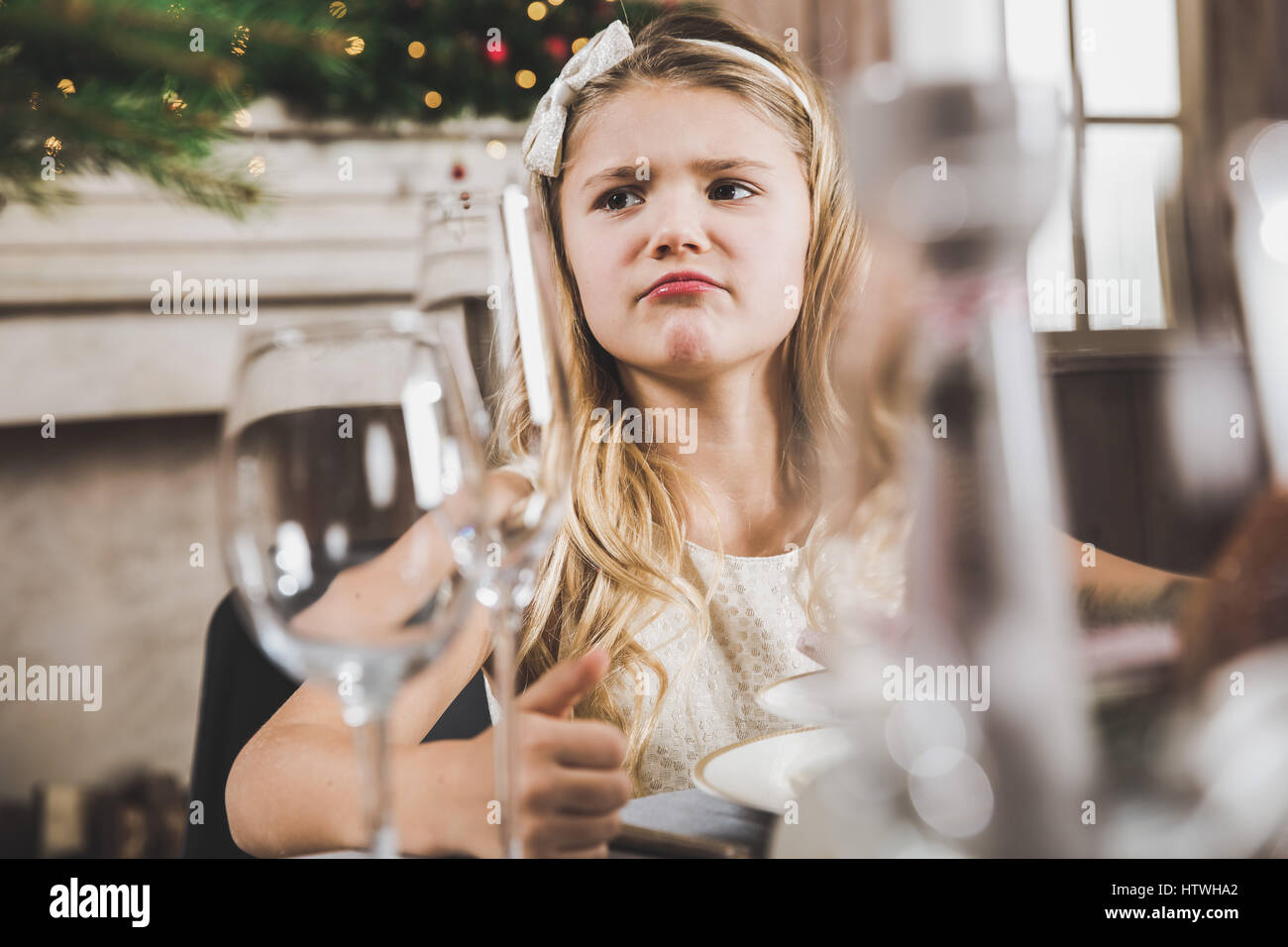 Niedliche kleine Mädchen am Urlaub Tisch sitzen und wegsehen zur Weihnachtszeit Stockfoto
