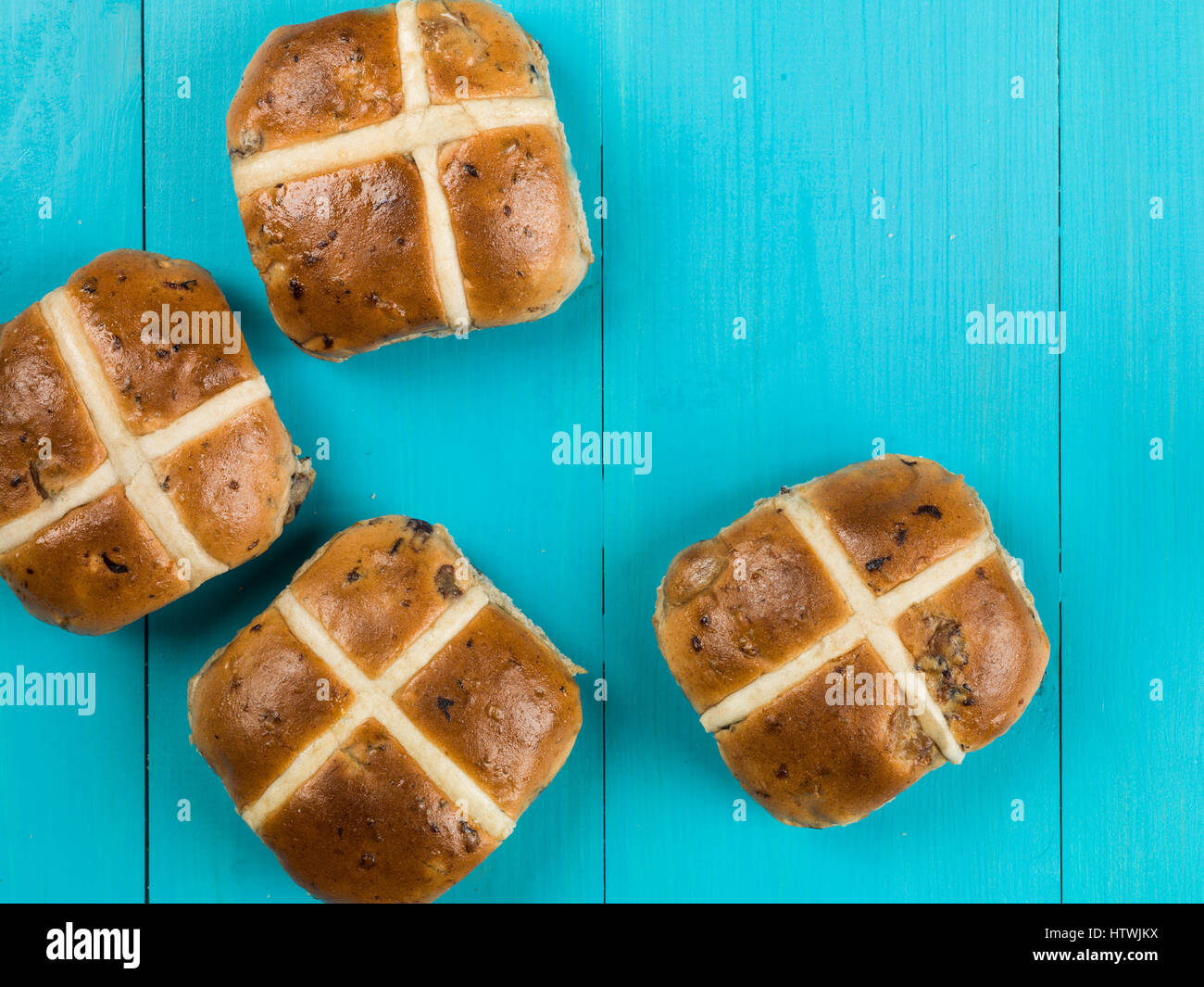 Vier Hot Cross Buns Kulinarische Ostern vor einem blauen Hintergrund Stockfoto