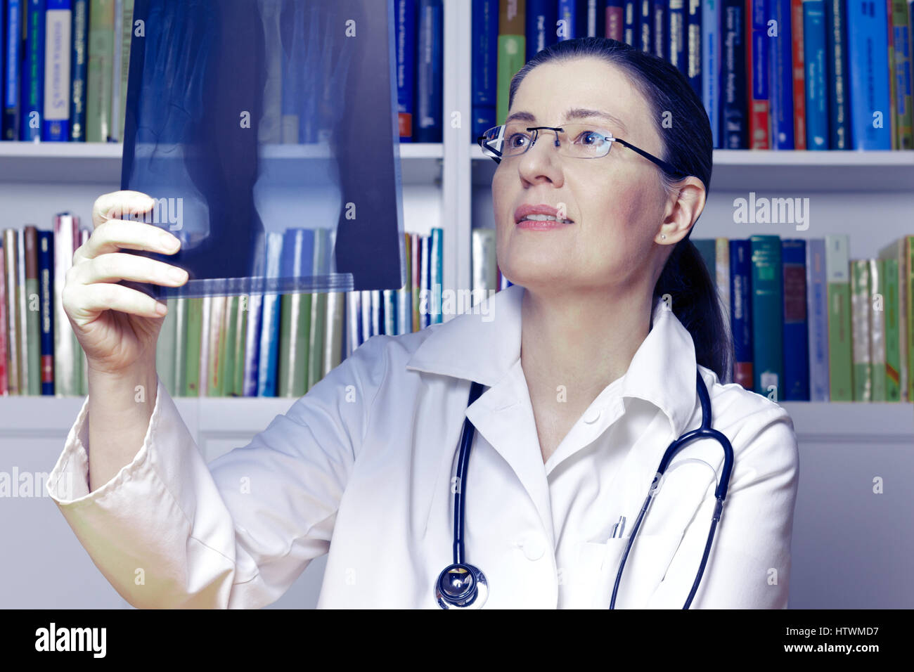 Weibliche Arzt oder Radiologen mit Stethoskop und ein x-ray von einem Fuß in der Hand wie durch eine Webcam, blauen Filter Effekt Stockfoto