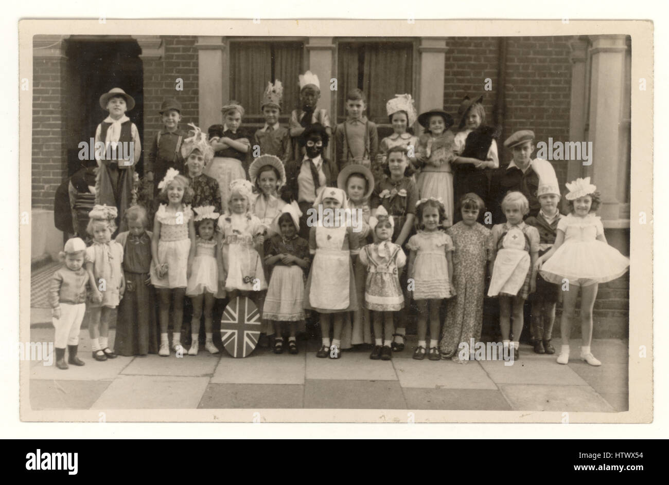Postkarte der Children's V.E. (Victory in Europe) Day Party und Feierlichkeiten, Partys wurden abgehalten, um das Ende des 2. Weltkriegs in Europa zu feiern - die Kinder sind in schicken Kleidern, in Cornwall Grove, Chiswick, London, Großbritannien, 8. Mai 1945 (zum Ende des Zweiten Weltkriegs), Kriegserinnerungen. Stockfoto