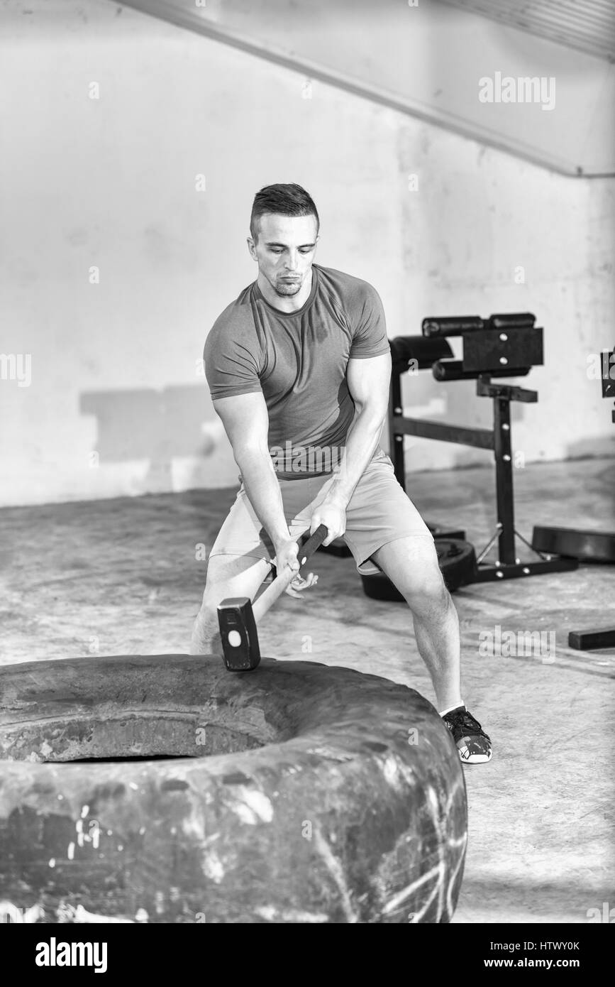 Vorschlaghammer Reifen Hits jungen muskulösen Mann Training im Fitness