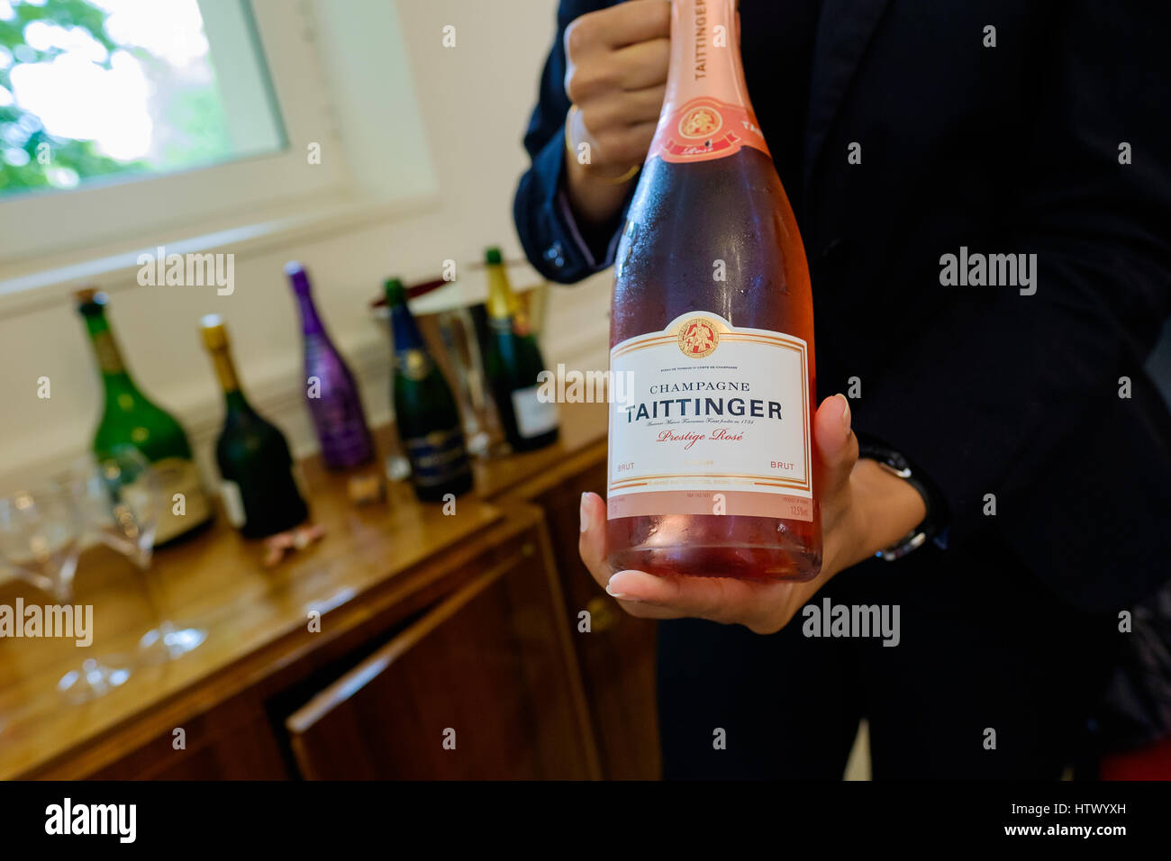 Flasche Taittinger Rosa Champagner von Frau zeigt Label gehalten Stockfoto