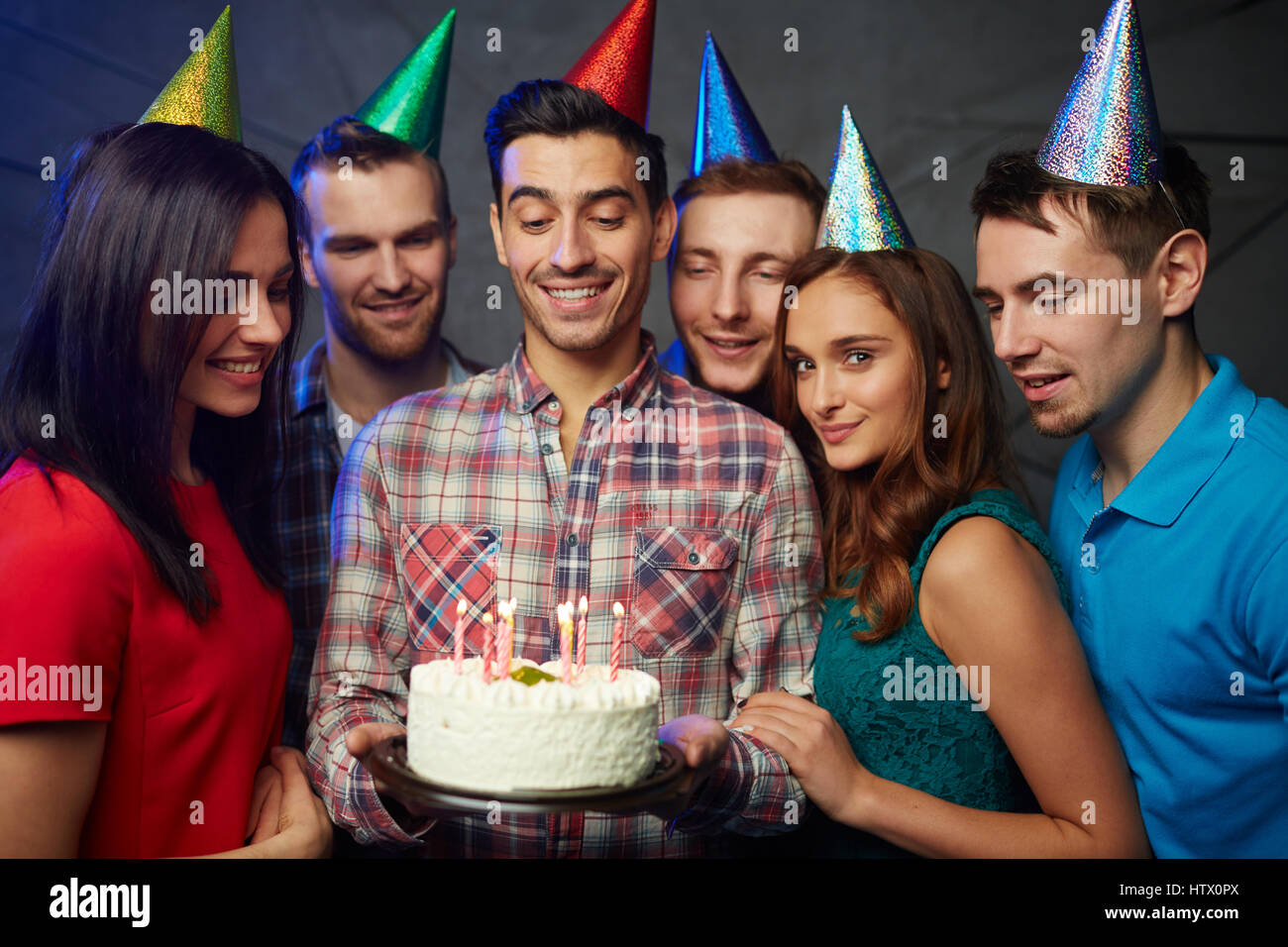Glückliche junge Freunde Blick auf brennende Kerzen auf leckere Geburtstagstorte Stockfoto