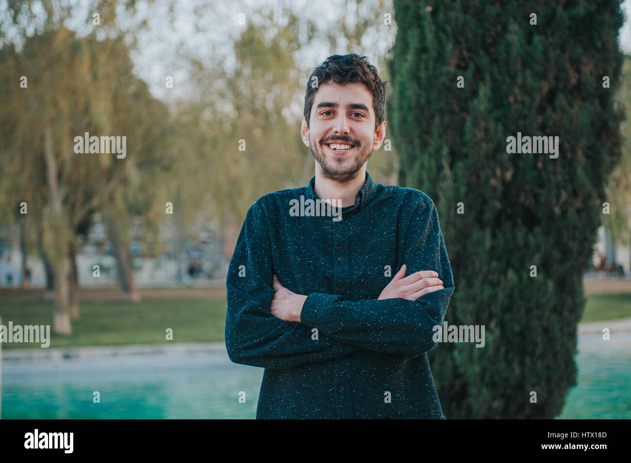 junge mexikanische Mann mit verschränkten Armen in einem park Stockfoto