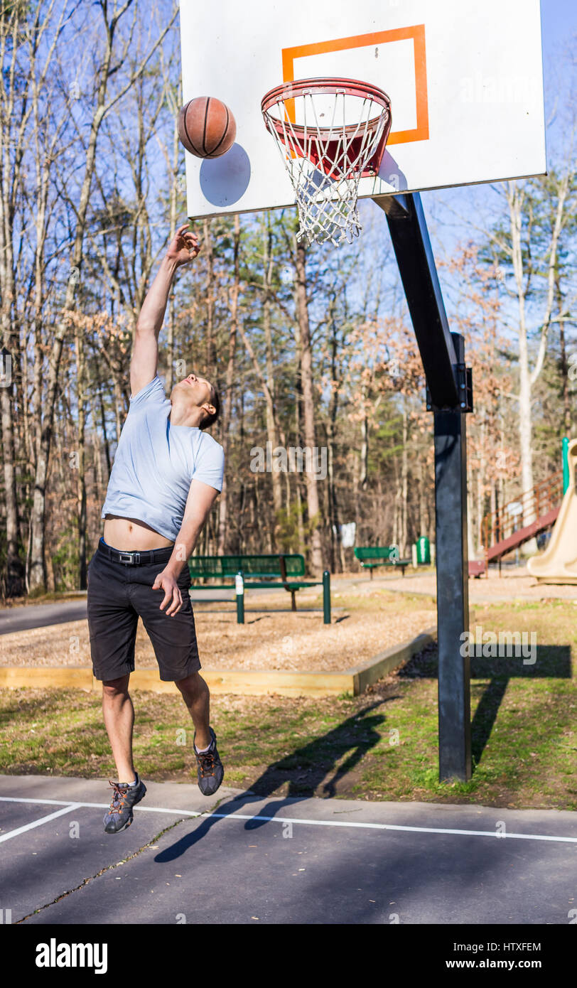 Young passen muskulösen Mann sprang werfen Basketball in Reifen Stockfoto
