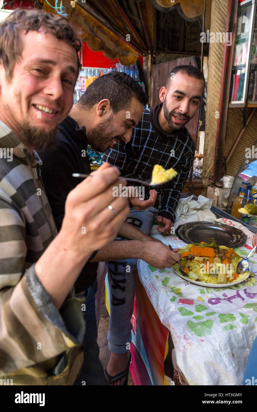 Fes, Marokko.  Drei junge Männer, die gemeinsame Mahlzeit in der Altstadt. Stockfoto