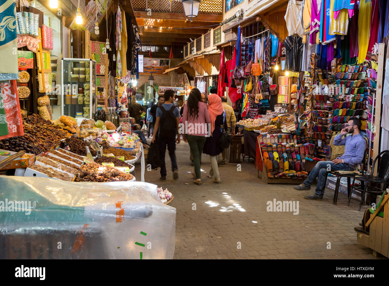 Fes, Marokko.  Straßenszene in Fès El-Bali, der alten Stadt.  Dörrobst, Leder Hausschuhe, Handtaschen. Stockfoto