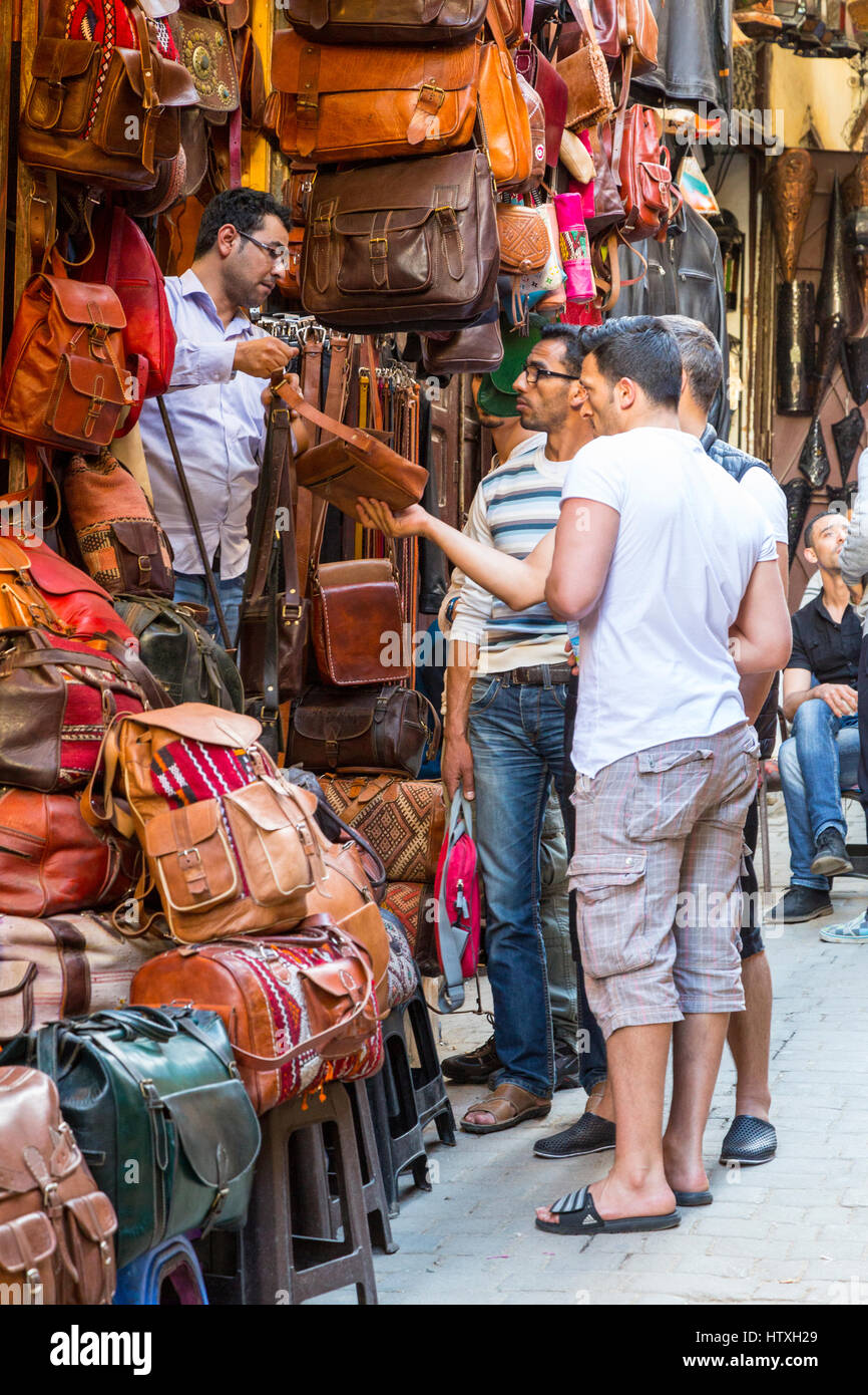 Fes, Marokko.  Straßenszene in der Medina.  Männer diskutieren Verkauf eine Ledertasche. Stockfoto