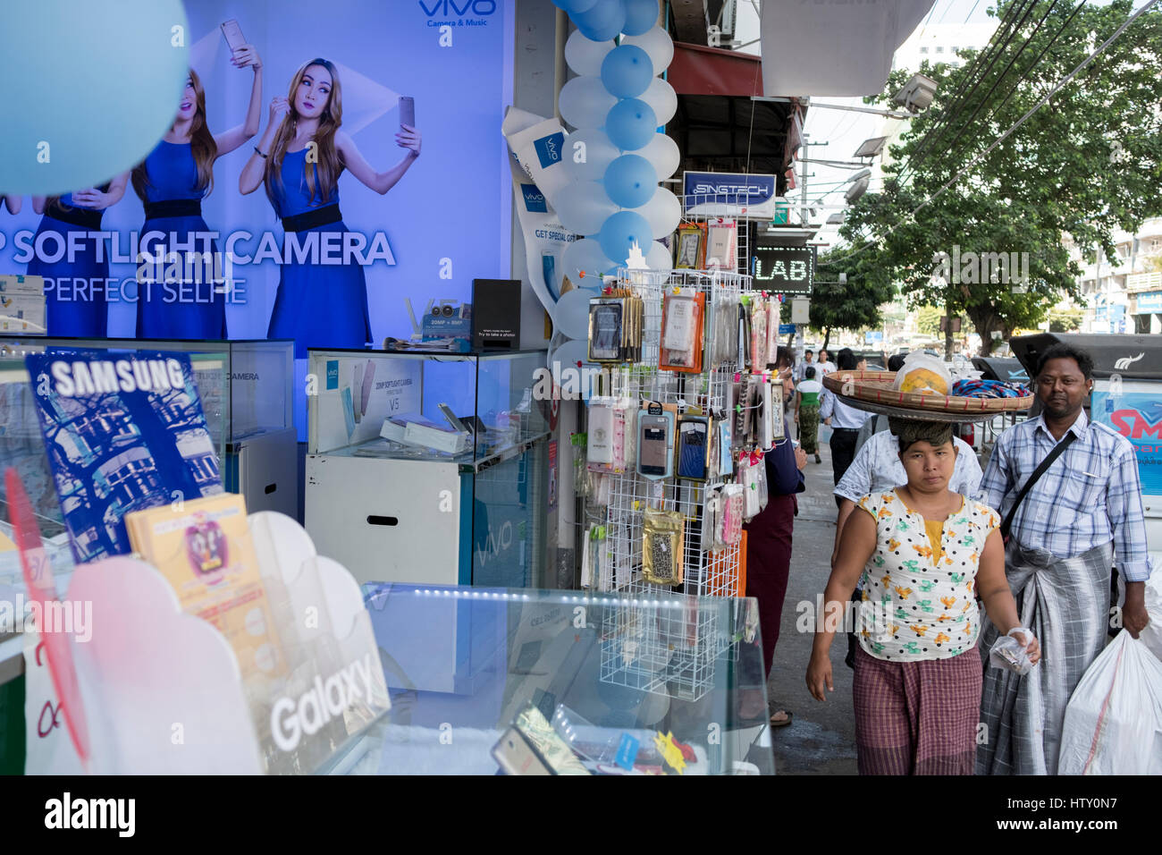 Fußgänger passieren einen Shop Verkauf von Mobiltelefonen in Anawrahta Road, Yangon, Myanmar Stockfoto