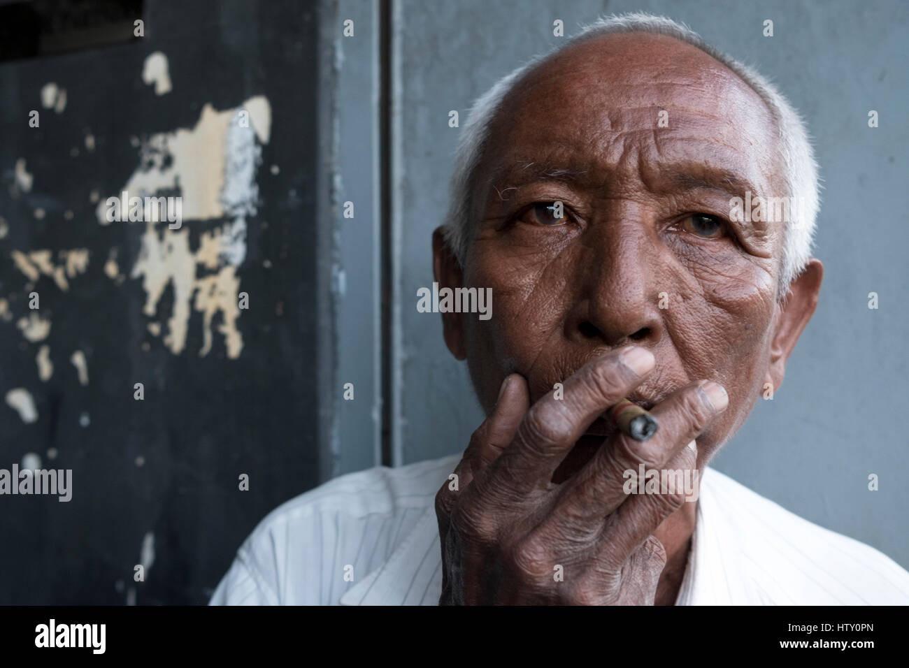 Eine ältere Gentelmen raucht eine Zigarre im Sule Pagoda Road, Yangon, Myanmar. Stockfoto