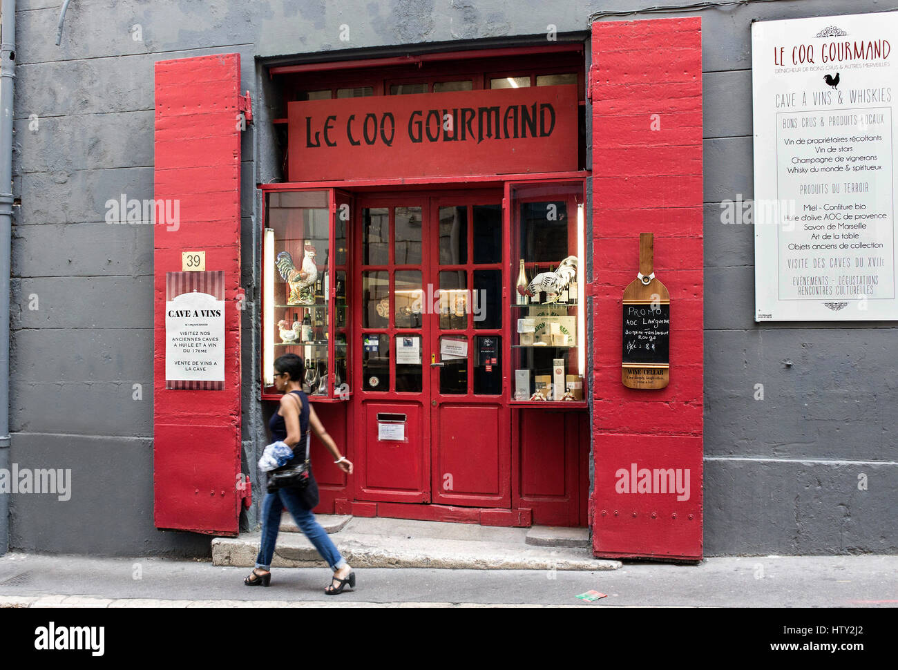 Roten hölzernen Doppeltüren Eingang ein Restaurant und eine Frau mit kurzen Haaren zu Fuß mit einer Tasche in Marseille, Frankreich. Stockfoto