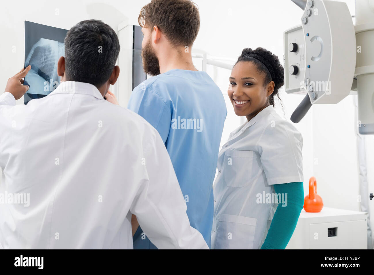 Weibliche Radiologen mit Kollegen analysieren Röntgen im Krankenhaus Stockfoto