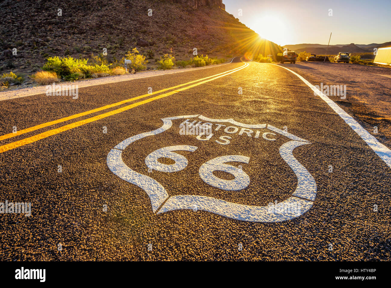 Straßenschild auf der historischen Route 66 in der Mojave-Wüste bei Sonnenuntergang gegen die Sonne fotografiert Stockfoto