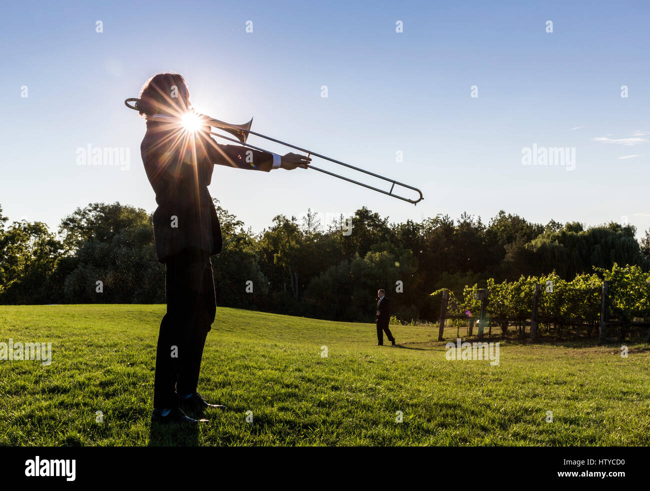 Musiker spielen eine Posaune im freien gegen einen blauen Himmel und Sonne platzen Stockfoto