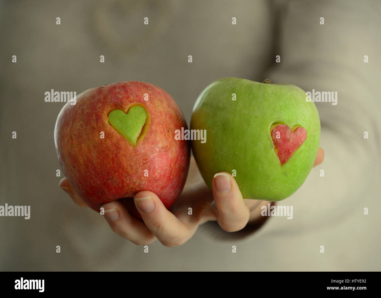 Frau mit roten und grünen Äpfeln mit Herzformen fehlt Stockfoto