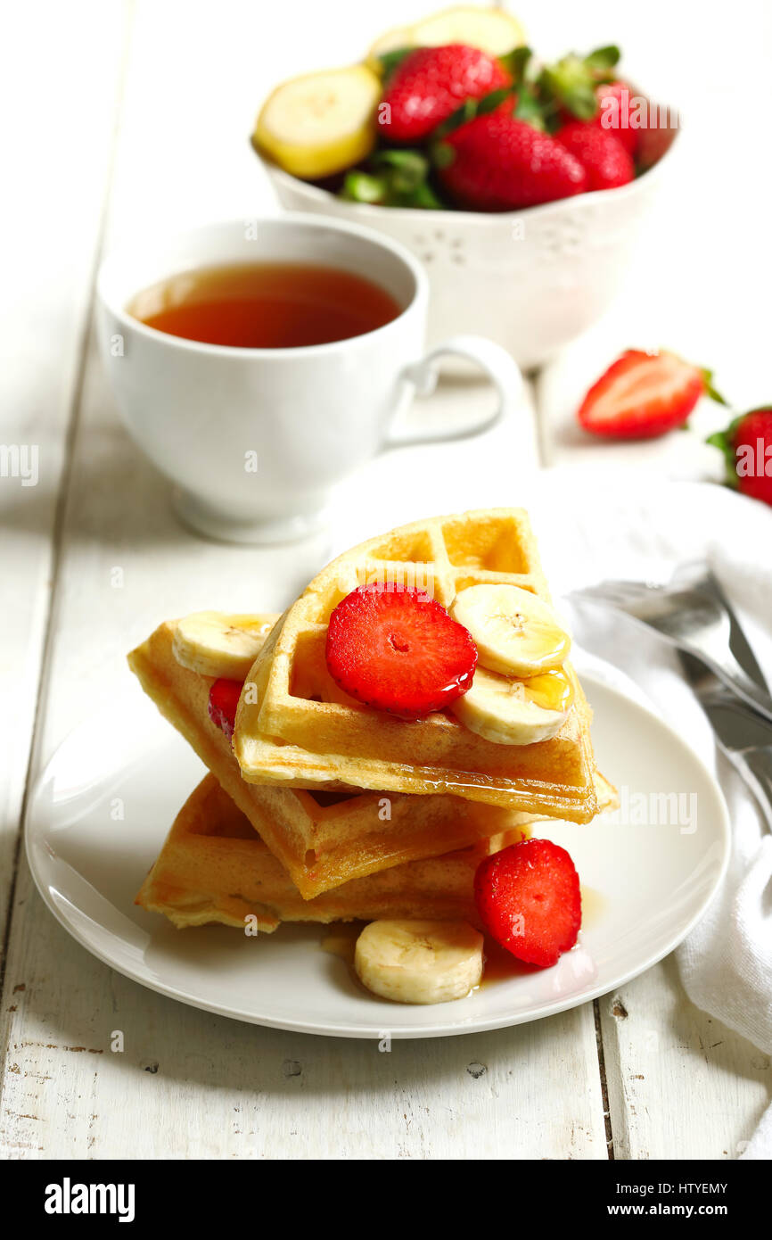 Tee und Waffeln mit Erdbeeren, Banane und Ahornsirup Stockfoto