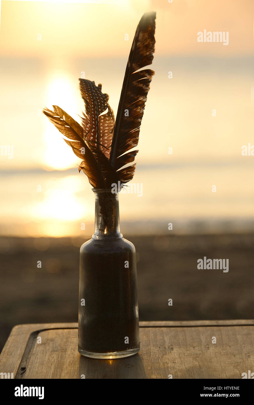 Federn in einer Glasflasche am Strand Stockfoto