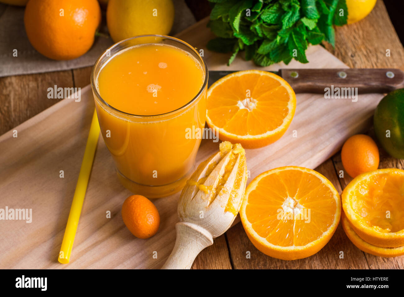 Zitrusfrüchte Orangen Zitronen Limetten, Kumquat, frischer Minze, Reibahle, frisch gepressten Saft im Glas auf Holz Küchentisch Fenster, Ansicht von oben Stockfoto