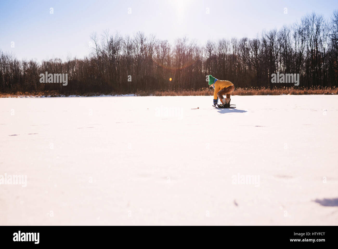 Junge in Schneeschuhen bücken Stockfoto