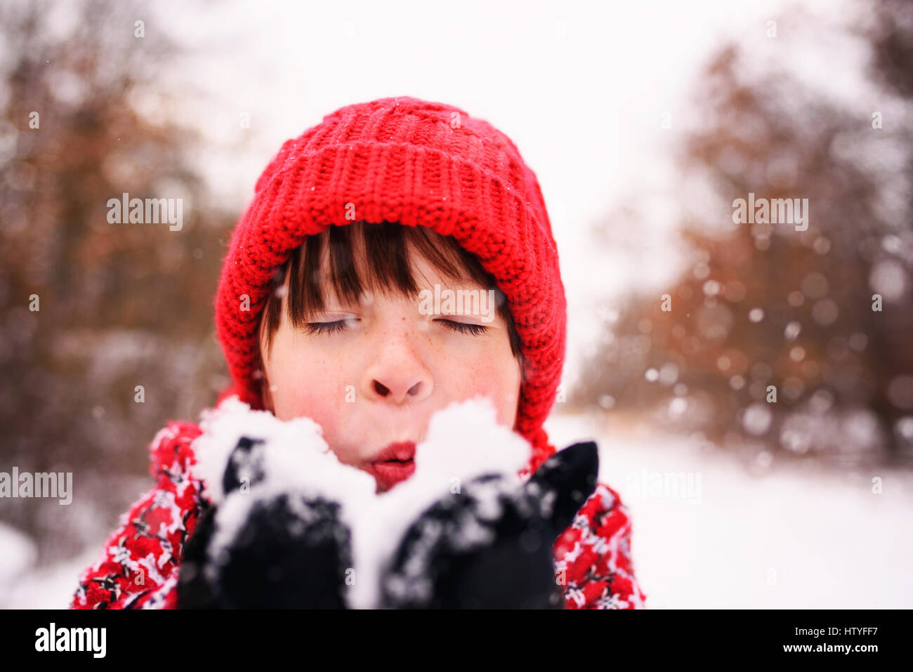 Mädchen bläst eine Handvoll Schnee Stockfoto