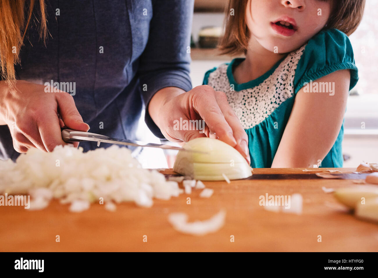 Mutter Unterricht ihrer Tochter Zwiebeln hacken Stockfoto