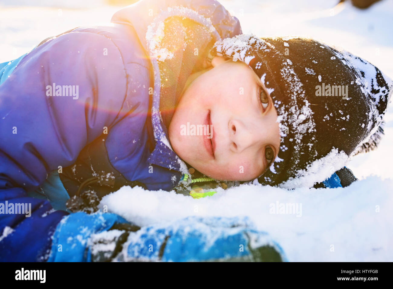 Portrait eines lächelnden jungen im Schnee liegen Stockfoto