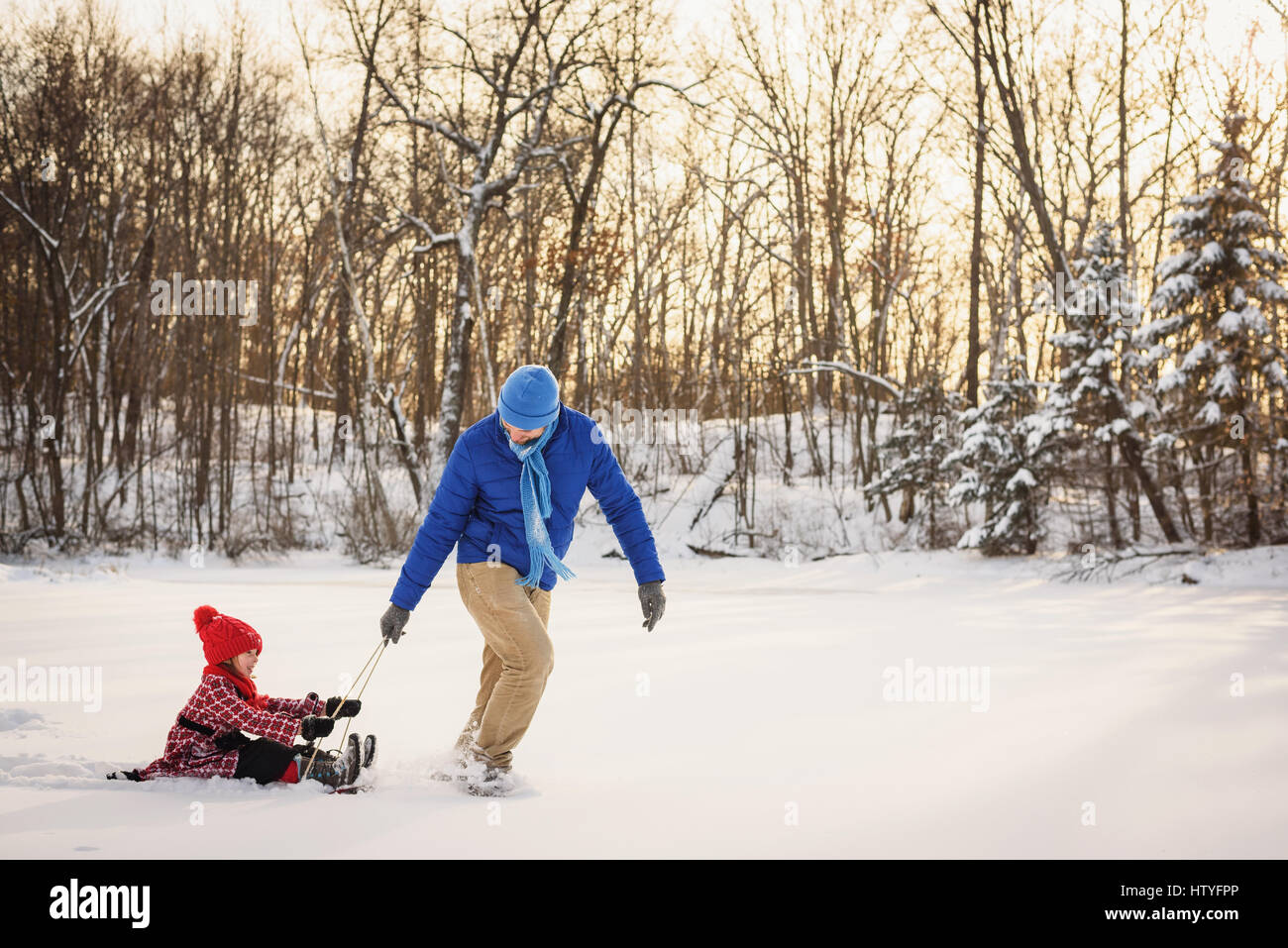 Vater Tochter auf einem Schlitten in den Schnee ziehen Stockfoto
