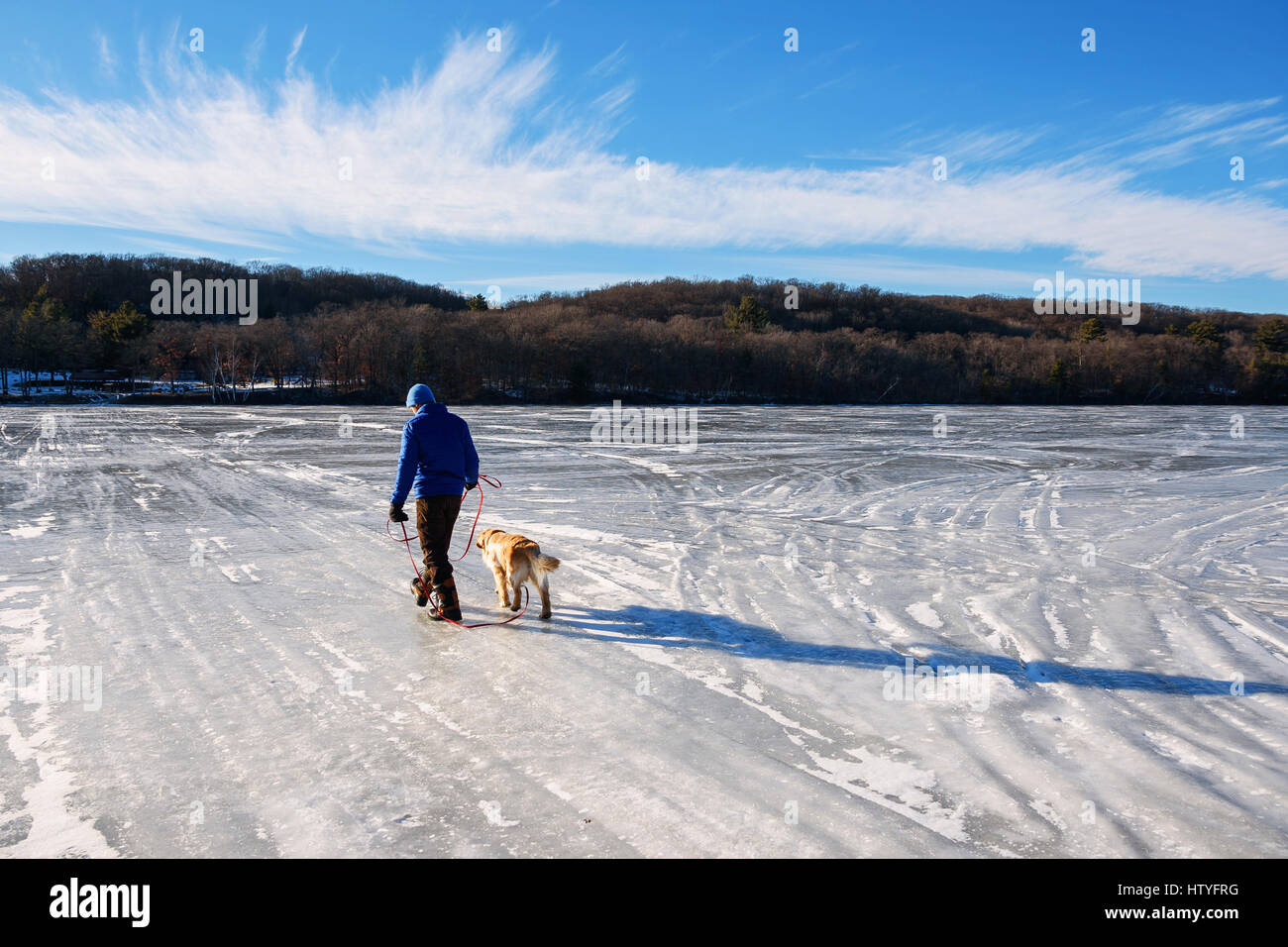 Mann geht seinen Hund über einen gefrorenen See Stockfoto