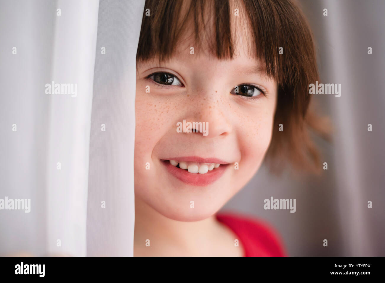 Porträt eines Mädchens durch einen Vorhang stehend Stockfoto