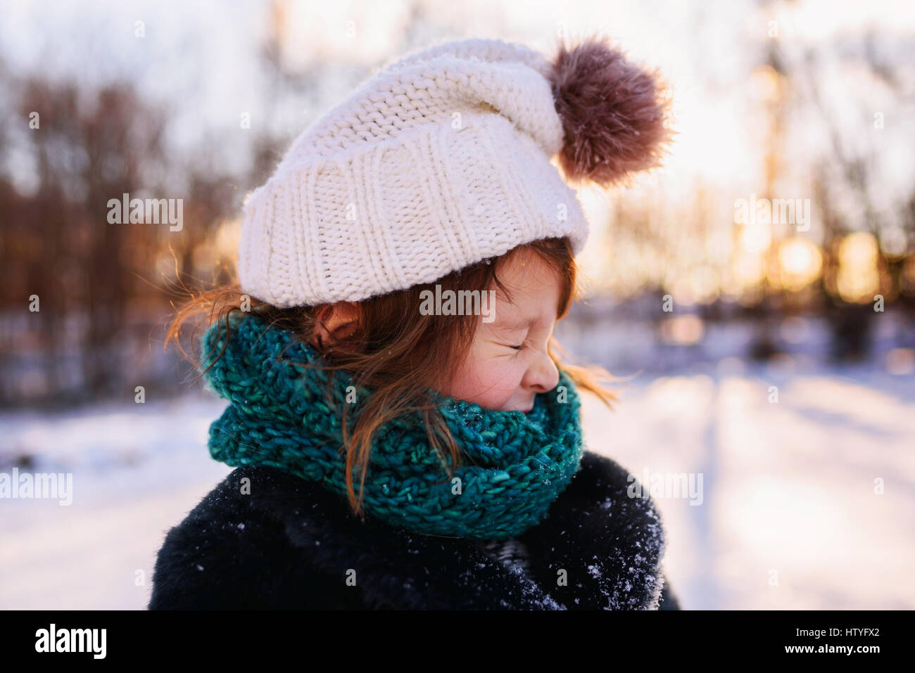 Mädchen in Pudelmütze und Schal im Schnee ziehen ein lustiges Gesicht stehen Stockfoto