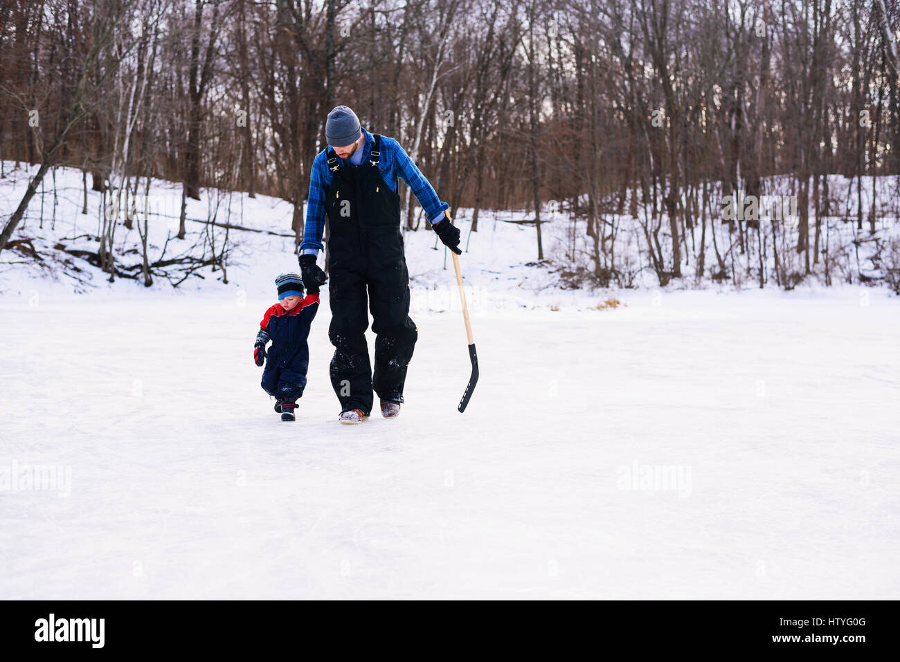 Vater zu Fuß über den zugefrorenen See mit seinem Sohn und Hockeyschläger Stockfoto