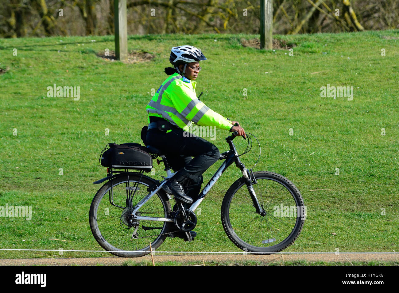 schwarze Polizistin patrouillieren auf dem Mountainbike in einem Park in England Stockfoto