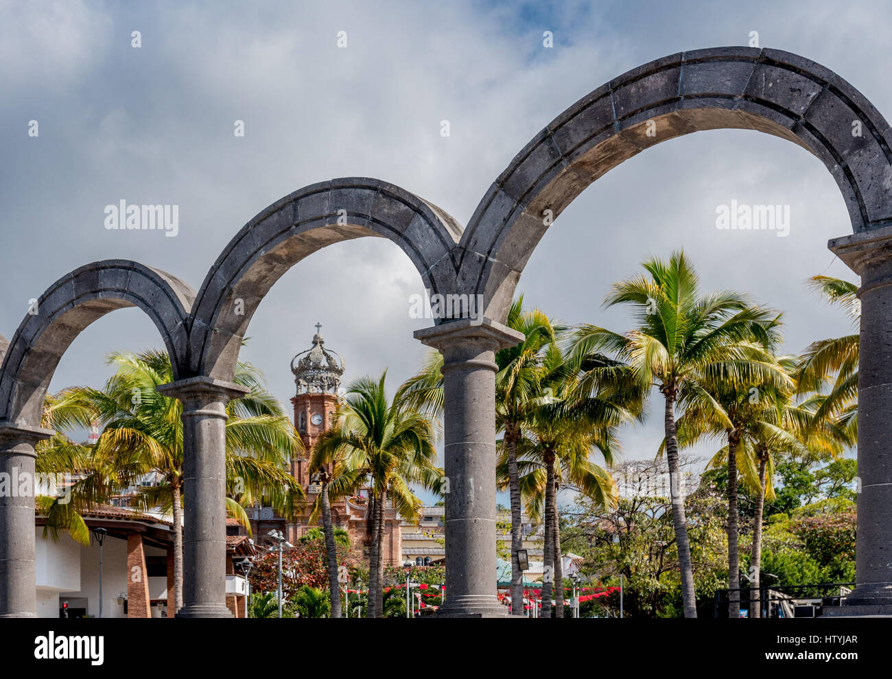 Blick auf Puerto Vallarta durch die Bögen oder Los Arcos auf dem Malecon zeigt Altstadt oder Old Vallarta und Our Lady of Guadalupe Church Tower. Stockfoto