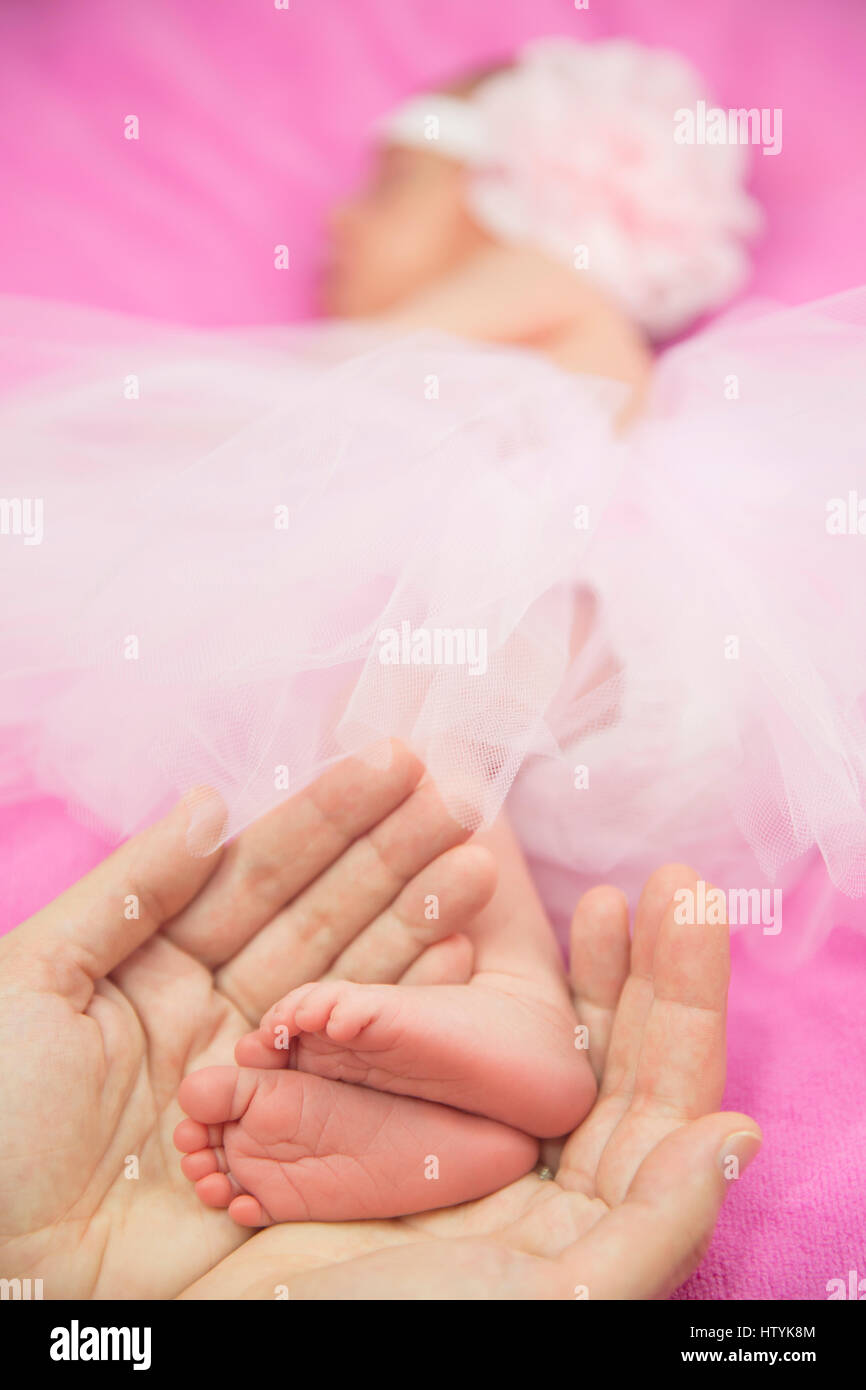 Frauenhand hält ein Babymädchen Füße Stockfoto